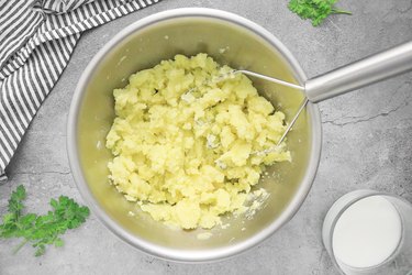 Mash potatoes with a vegetable masher