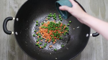 adding veggies to wok