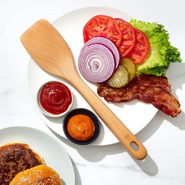 wooden spatula  by OXO on a plate with hamburger toppings