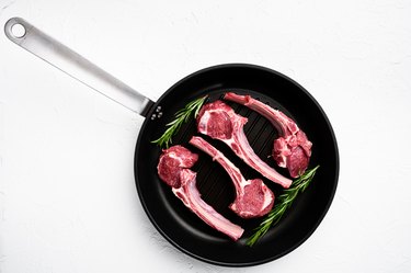 Raw lamb chops and rosemary in a carbon steel pan