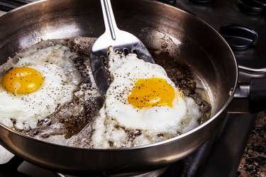 High Angle View Of Fried Eggs In Cooking Pan On Stove