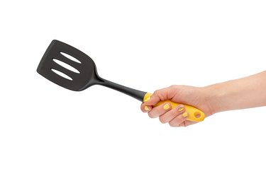 Woman\'s hand holding spade for frying pan. Isolated on white.