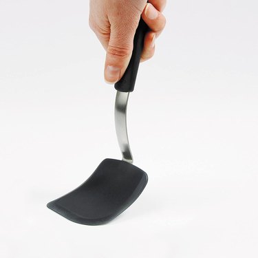 OXO spatula showing its flexibility, on a grey ground