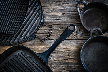 Cast iron pans and grills on rustic wooden table