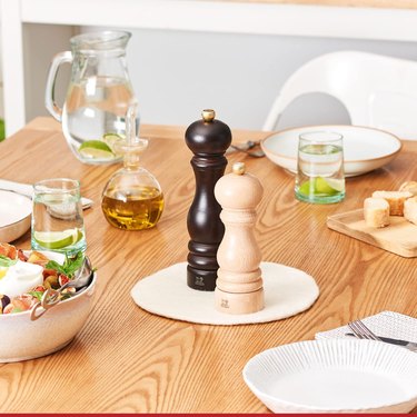 Peugeot pepper grinders on a table with multiple place settings