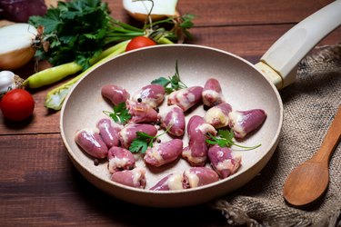 Fresh chicken heart on a frying pan with cooking ingredients