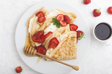 Summer treat, healthy breakfast with crepes, fresh strawberry, cheese and coffee