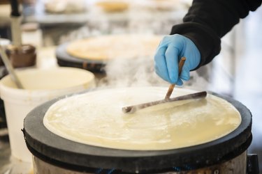Making crepes on a steaming hot griddle