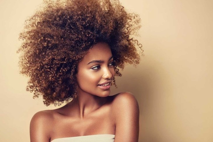 Beauty portrait of african american black woman with clean healthy skin on beige background. Skin care and cosmetic. Smiling beautiful afro girl.Curly hair