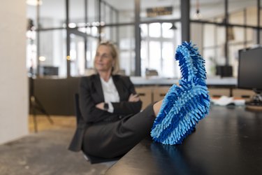 Woman with feet on desk wearing cleaning slippers