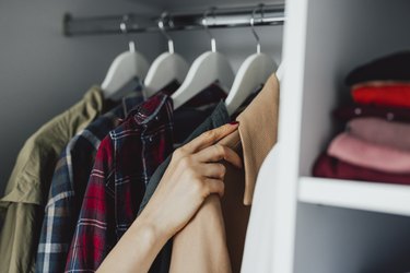 Close Up Photo of Woman Hands Choosing Clothes on a Rack at Home