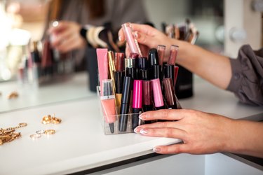 Young woman is neatly organizing her lipstick, lip gloss in the makeup storage at home