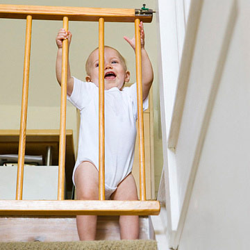 baby holding onto gate on stairs