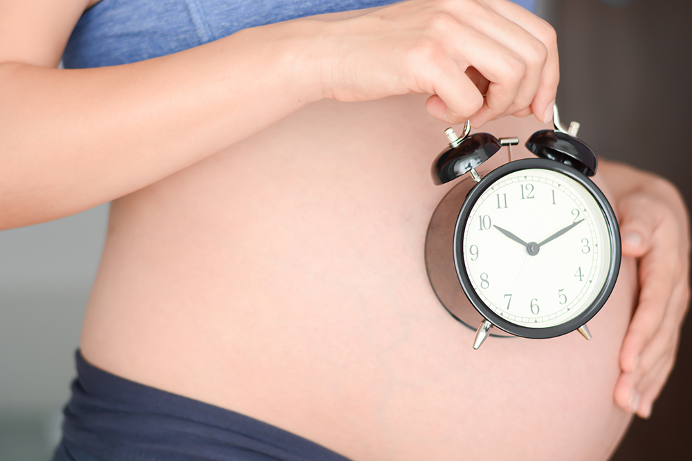 pregnant woman holding alarm clock
