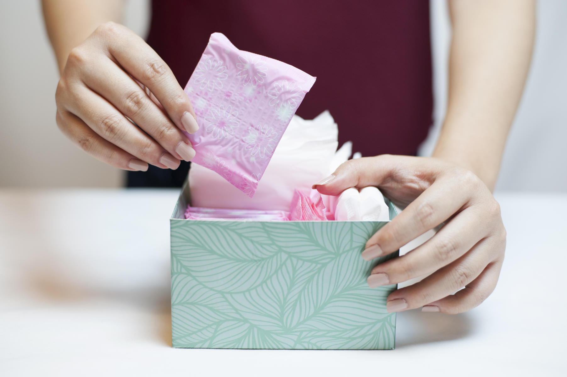 Woman Holding Pad From Box Of Feminine Supplies
