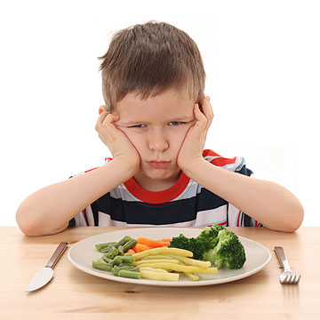 angry boy with plate of vegetables