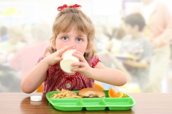 Girl eats school lunch in cafeteria