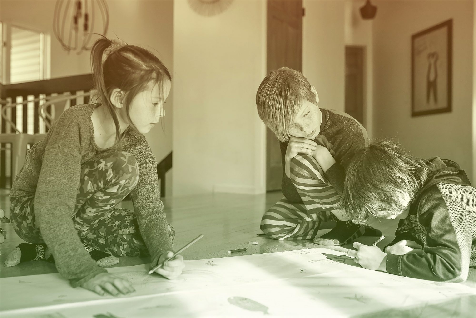 Three young children working on an art project at home