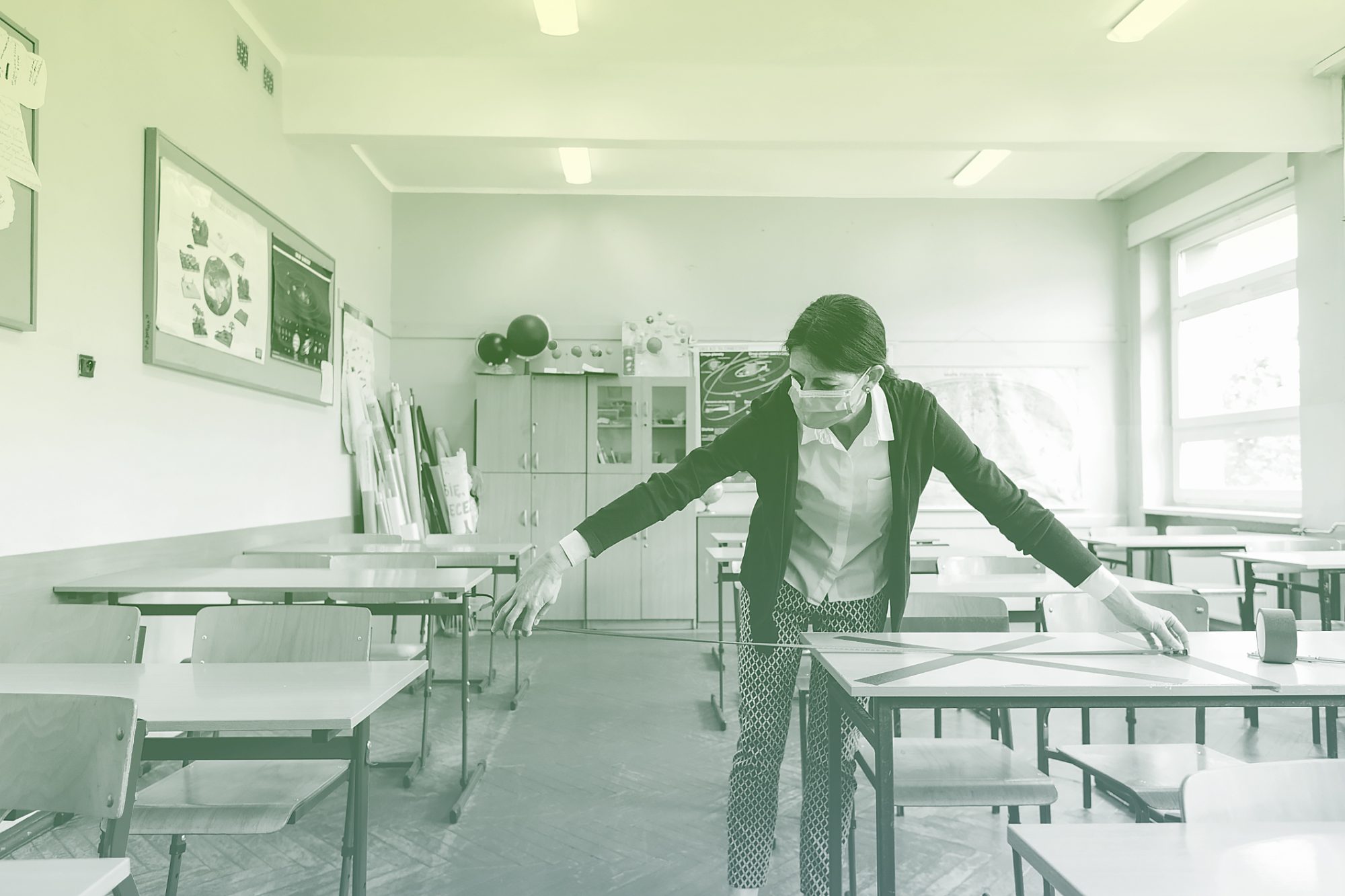 teacher measures distance between desks in classroom